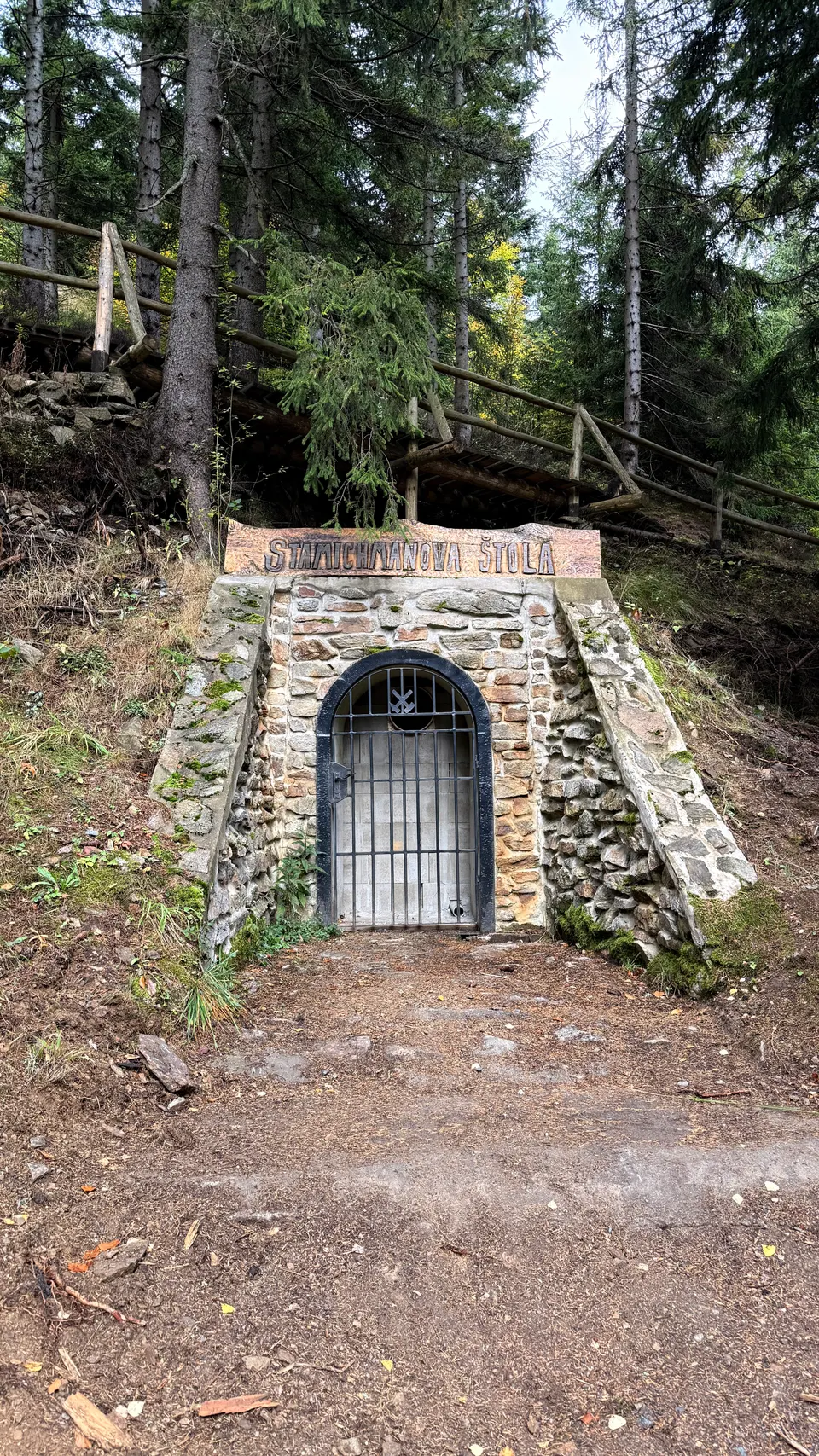 林子裡的石砌坑道口,招牌上寫著 štola(坑道)。