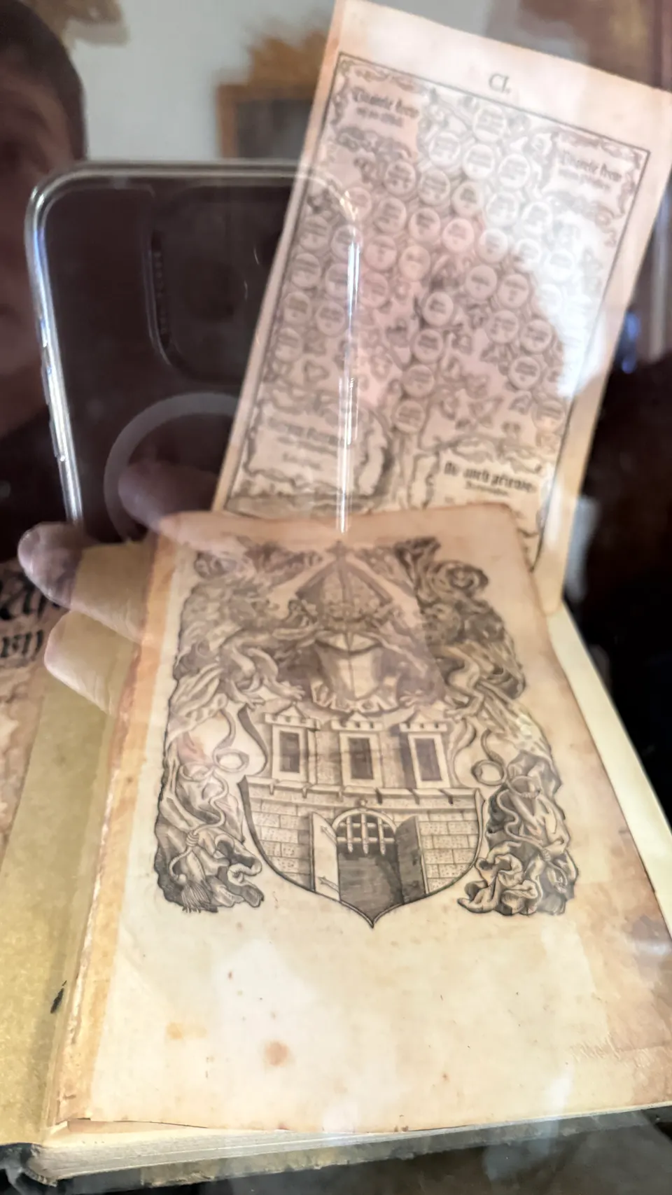 一本攤開的老書，玻璃上映著手機。