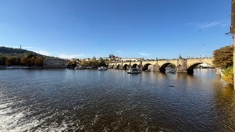 從河岸看查理大橋，水面亮晶晶的。