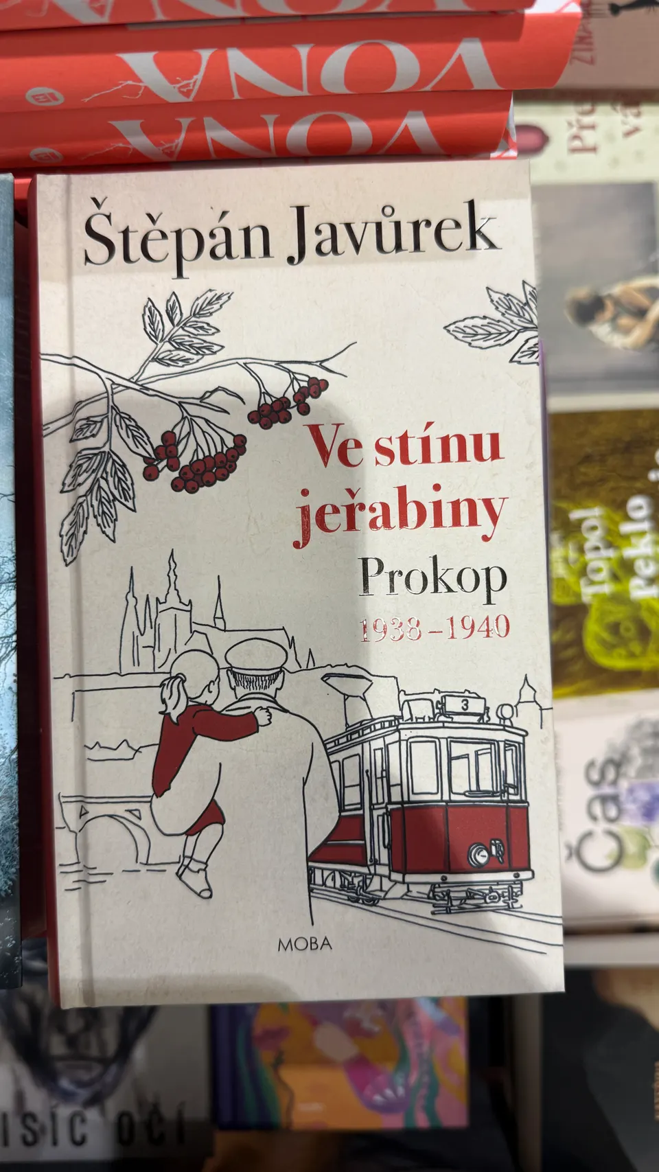書架上的《Ve stínu jeřabiny》，封面畫著一輛布拉格電車。